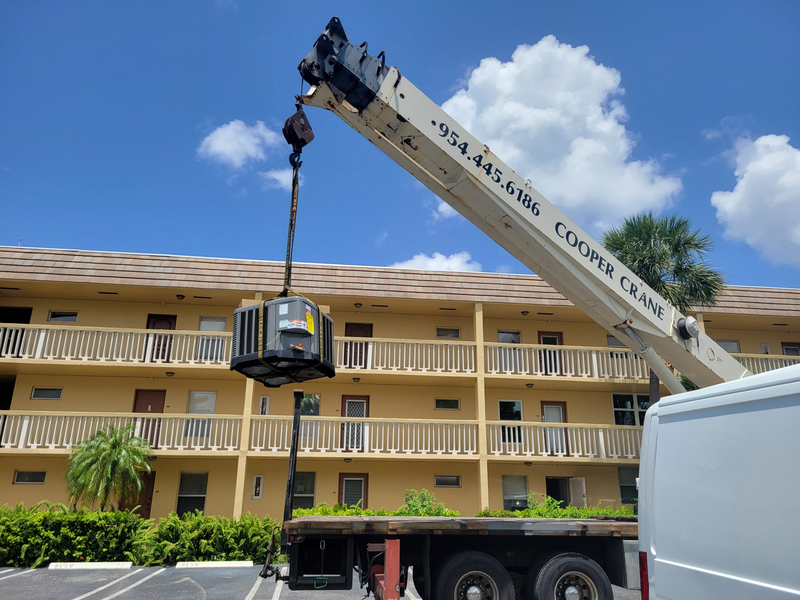 Crane lifting an outdoor air-conditioning unit at a commercial building